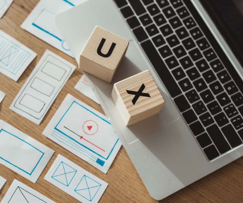 Lettres U et X en bois sur un bureau avec maquettes de site web et ordinateur portable.