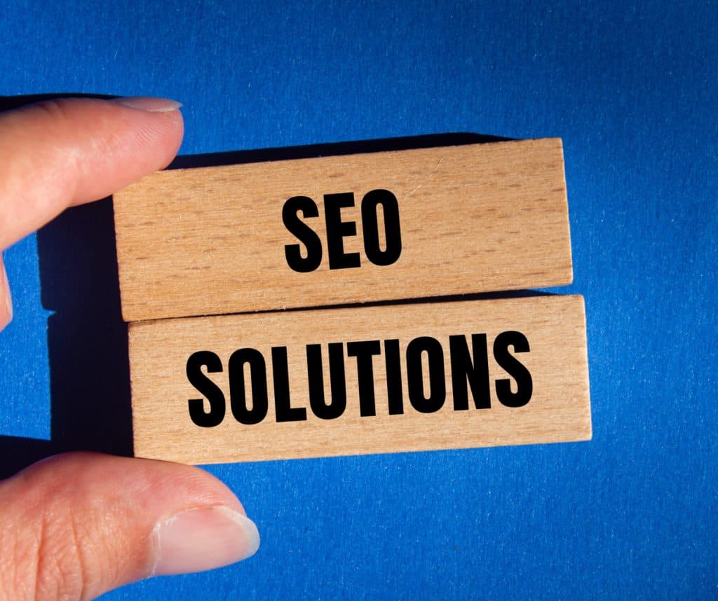 Bloc de bois avec "SEO SOLUTIONS" en lettres noires.