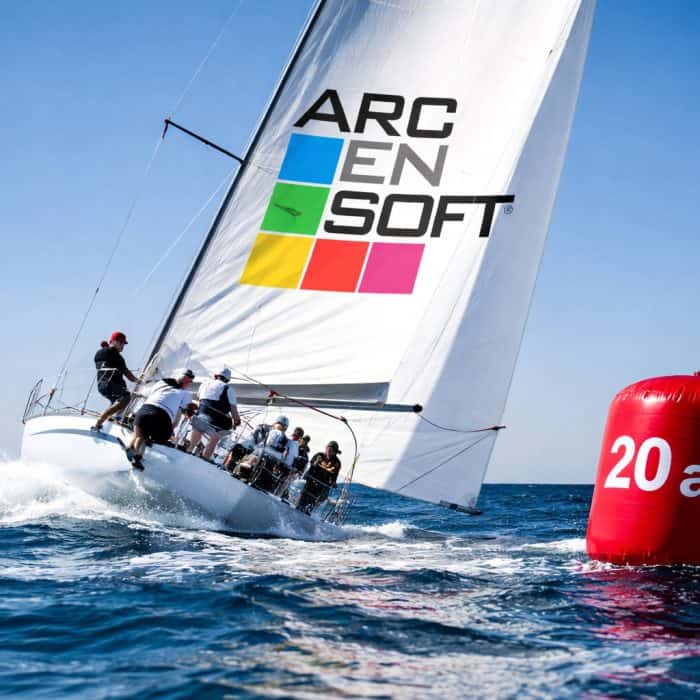 Voilier de course avec équipage naviguant près d'une bouée rouge "20 ans".