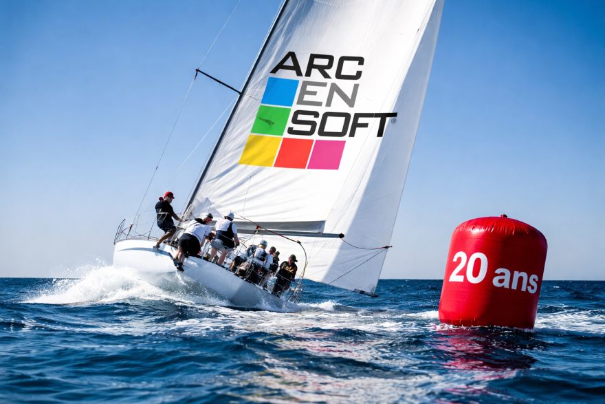 Voilier de course avec équipage naviguant près d'une bouée rouge "20 ans".
