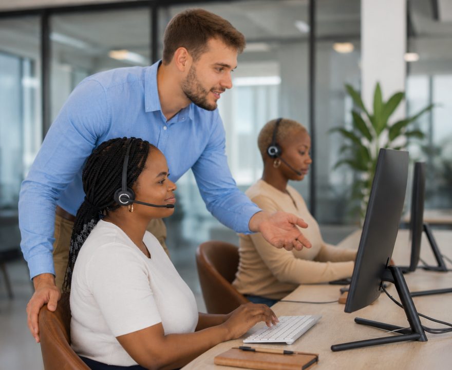 Formateur aidant deux agents au support client en centre d'appel.