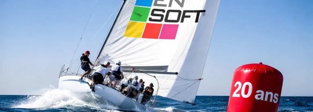 Voilier de course avec équipage naviguant près d'une bouée rouge "20 ans".