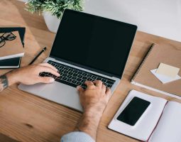 Personne utilisant un ordinateur portable sur un bureau en bois.